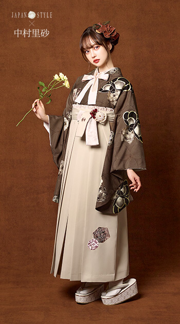黒い花の模様をあしらった白の着物とグレーの袴を着たモデル